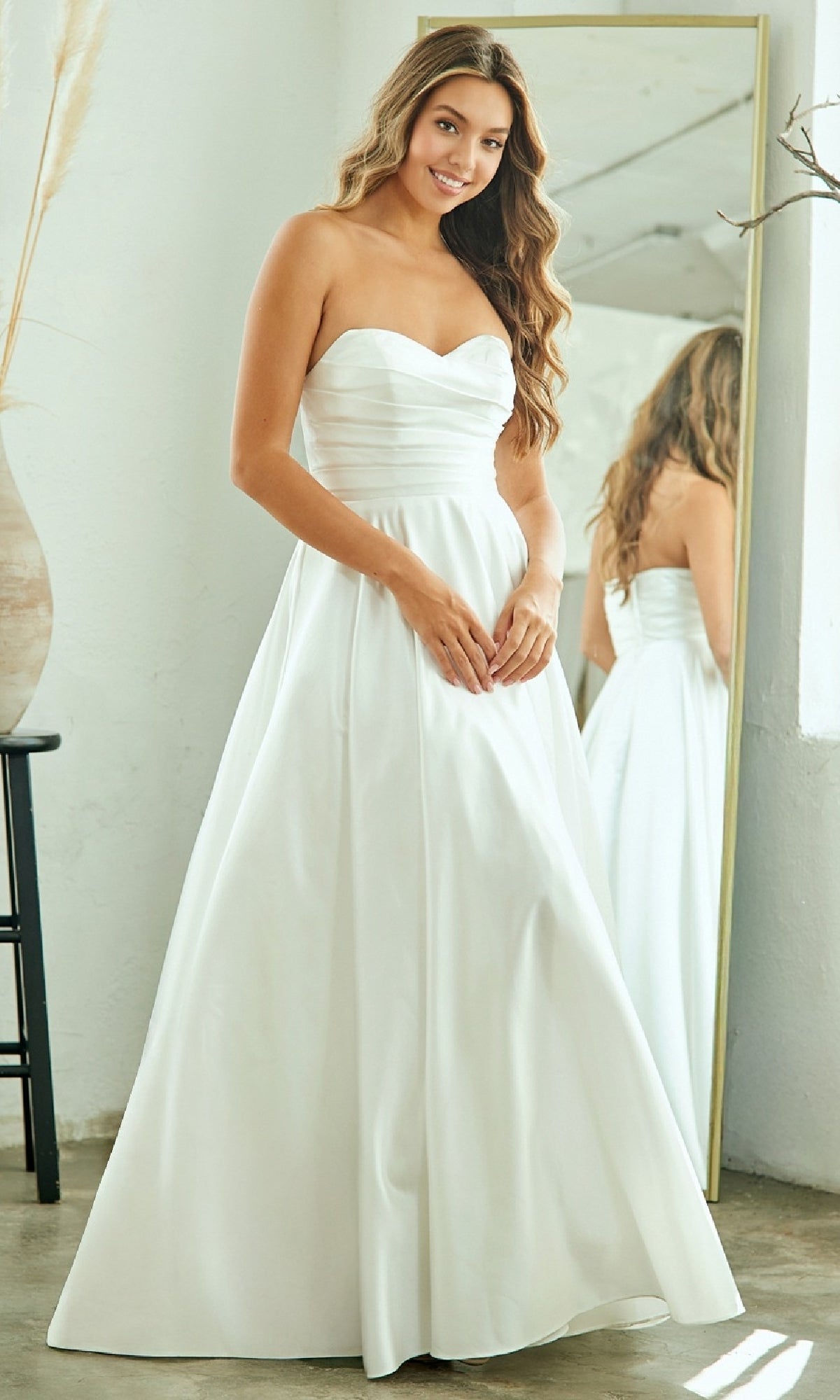 Woman in a strapless white evening gown standing in front of a mirror.